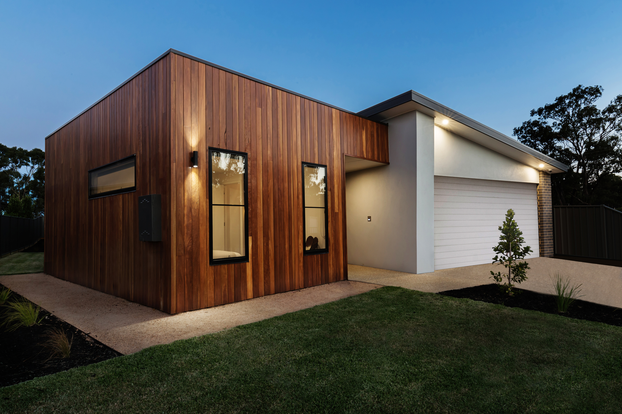 Modern house with wooden facade and attached garage at dusk