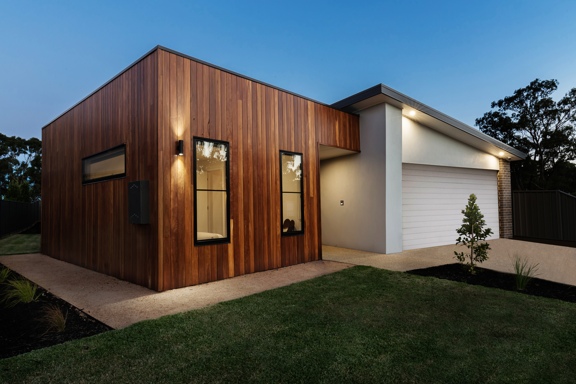 Modern house with wooden facade and attached garage at dusk - Expert Tips for Designing Custom Security Lighting for Small Properties