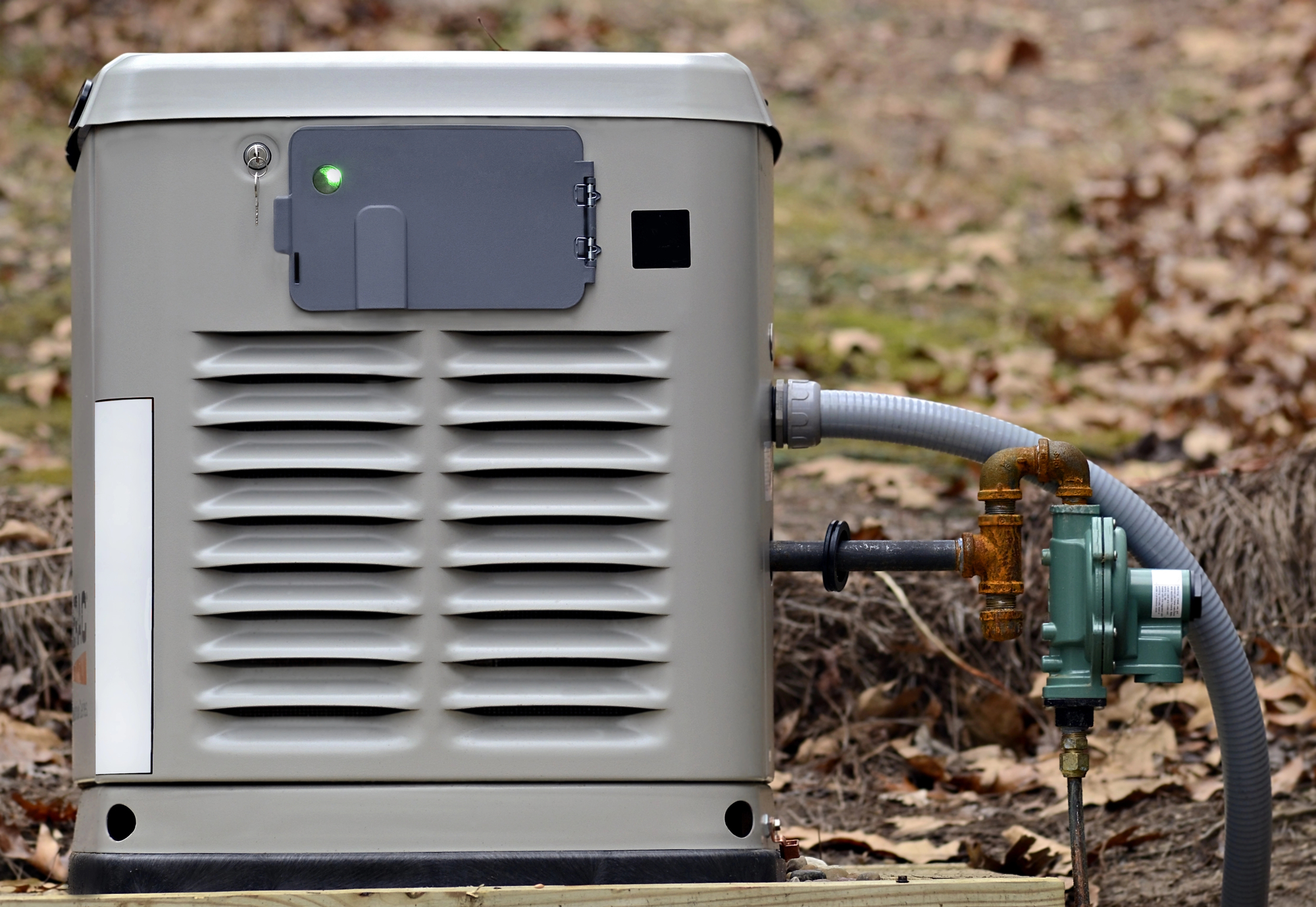 A standby home generator connected to a gas supply line in a residential backyard